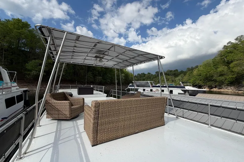 Slide: The Image of 1989 Sumerset 14x63 houseboat with outdoor seating under canopy, docked by lush greenery. - 35