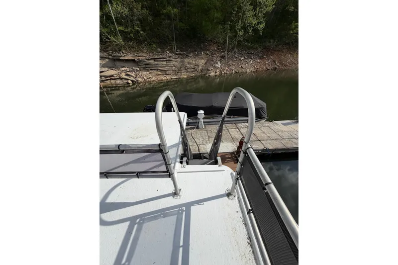 Slide: The Image of 1989 Sumerset 14x63 houseboat with dock ladder, moored by a wooded shoreline. - 37