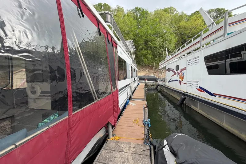 Slide: The Image of 1989 Sumerset 14x63 houseboat docked between two others on a calm lake. - 45