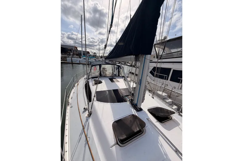 Slide: The Image of 1998 Hunter Legend 40.5 sailboat docked, showcasing deck and rigging under cloudy sky. - 17