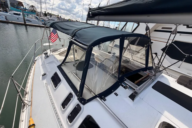 Slide: The Image of 1998 Hunter Legend 40.5 sailboat docked, featuring a covered cockpit and American flag. - 18