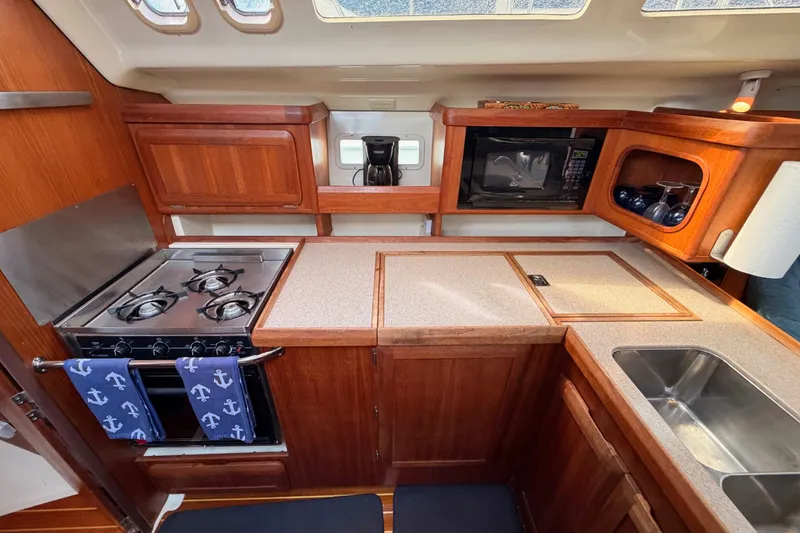 Slide: The Image of 1998 Hunter Legend 40.5 yacht kitchen with stove, microwave, and wooden cabinetry. - 36