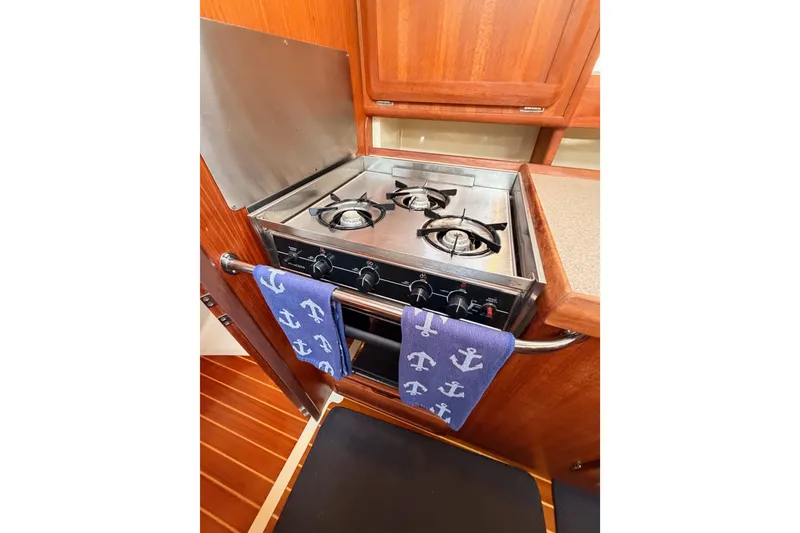 Slide: The Image of 1998 Hunter Legend 40.5 yacht kitchen with stove and anchor-themed towel. - 37