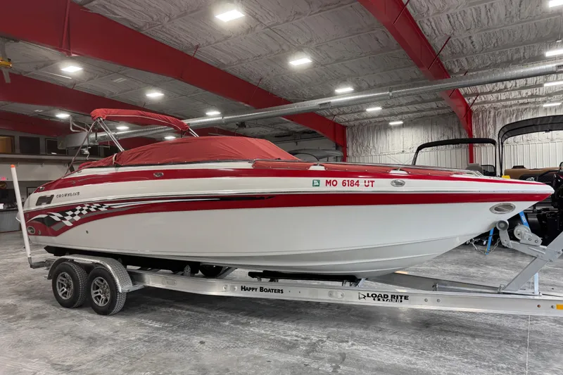 Slide: The Image of 2003 Crownline 270 BR boat with red cover on trailer in indoor storage. - 13