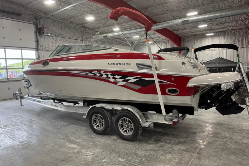 Slide: The Image of 2003 Crownline 270 BR boat with red and white design on a trailer in a garage. - 3