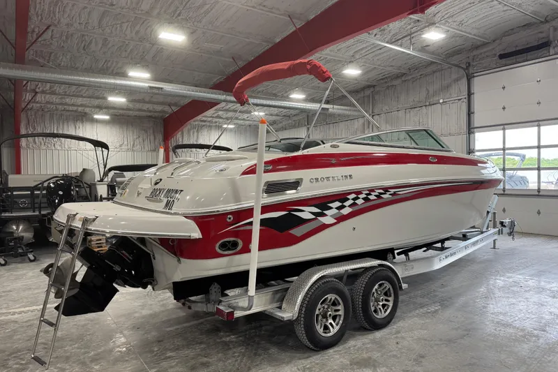 Slide: The Image of 2003 Crownline 270 BR boat in a garage, red and white design, on a trailer. - 4