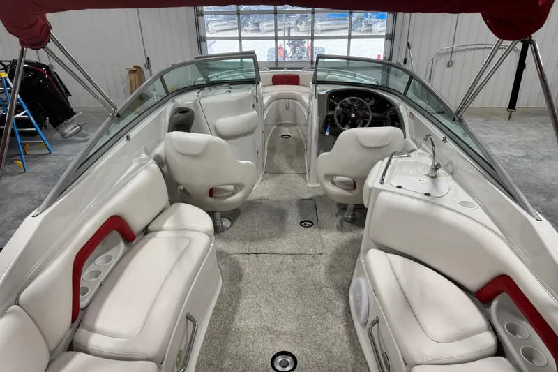 Slide: The Image of 2003 Crownline 270 BR boat interior with white seating and red accents in a garage setting. - 6