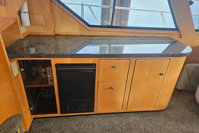Slide: The Image of Wooden cabinet with granite countertop and mini fridge on a 1995 Symbol 55 boat. - 10