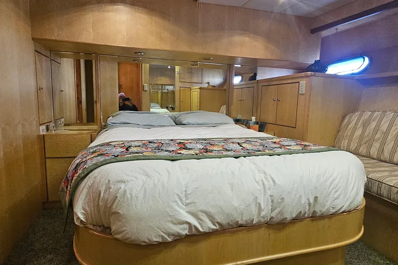 Slide: The Image of Cozy bedroom interior on a 1995 Symbol 55 yacht, featuring a comfortable bed and wooden cabinetry. - 27