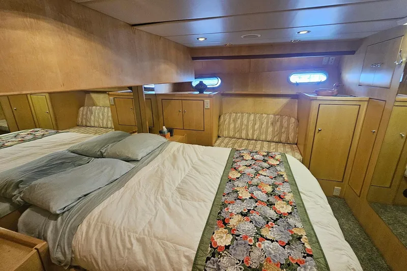 Slide: The Image of Cozy 1995 Symbol 55 yacht bedroom with floral bedspread and wooden cabinetry. - 29