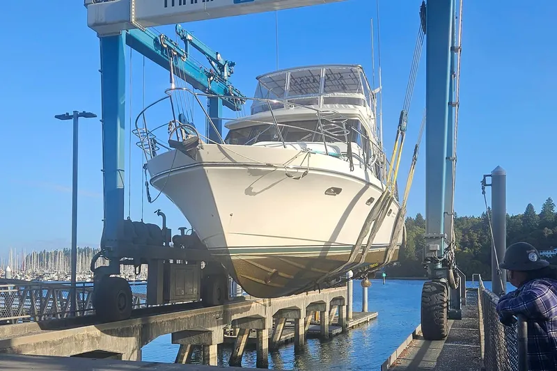 Slide: The Image of A 1995 Symbol 55 yacht being lifted by a boat hoist at a marina. - 3