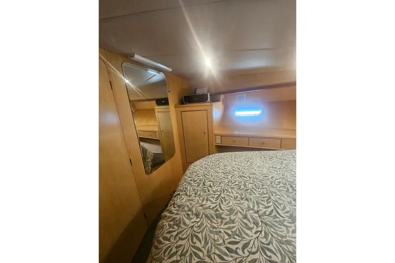 Slide: The Image of Cozy bedroom interior in a 1995 Symbol 55 yacht, featuring wood paneling and patterned bedding. - 34