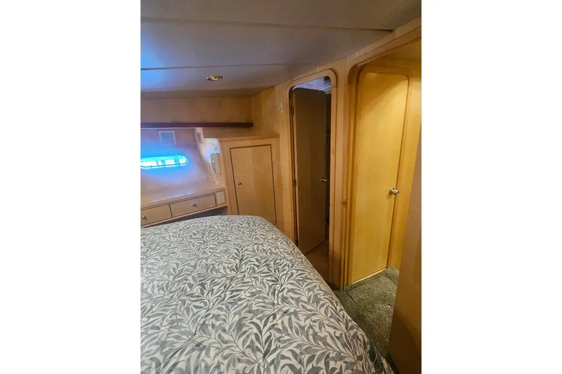 Slide: The Image of Cozy bedroom interior in a 1995 Symbol 55 yacht, featuring wood paneling and patterned bedding. - 35