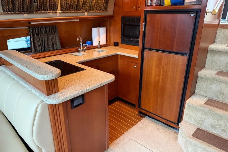 Slide: The Image of Luxurious 2003 Cruisers Yachts 405 Express Motoryacht kitchen with wood cabinetry and modern appliances. - 34