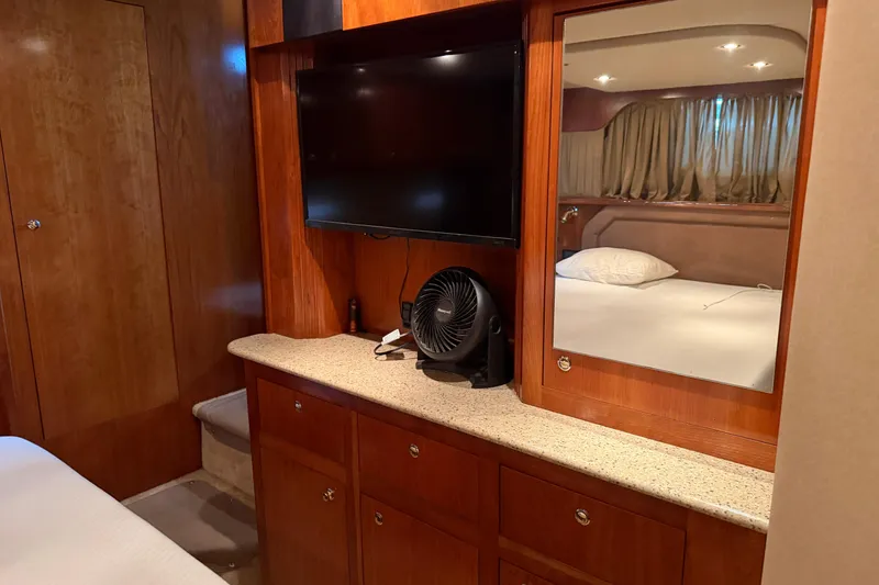 Slide: The Image of Luxurious 2003 Cruisers Yachts 405 Express Motoryacht cabin with TV, mirror, and wooden cabinetry. - 57