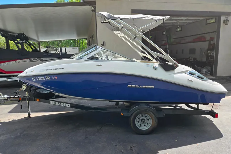 The Image of 2011 Sea-Doo 180 Challenger SE boat on trailer, parked outdoors. - 1