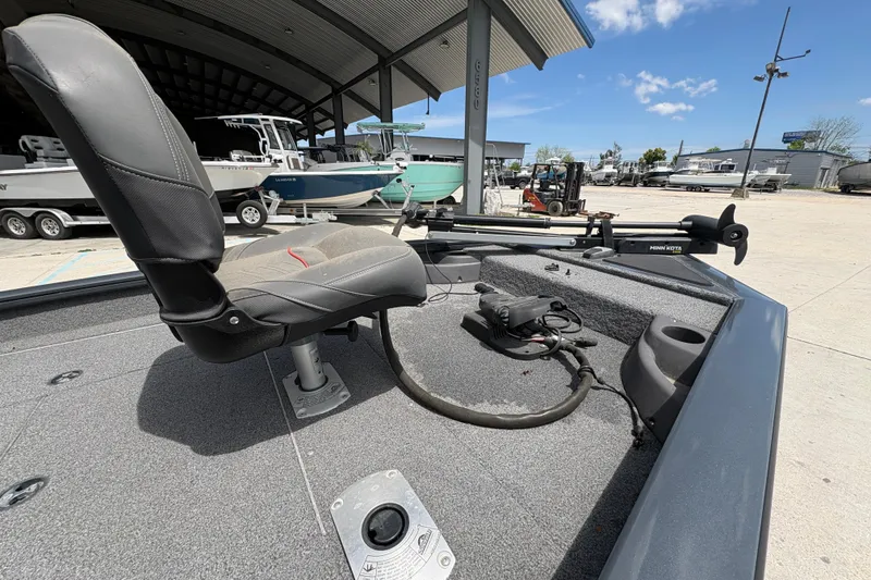 Slide: The Image of 2022 Tracker Pro Team 175 boat interior with seat and trolling motor in a marina. - 12