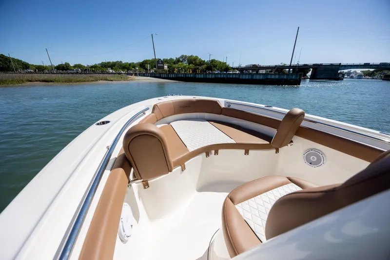 Slide: The Image of 2022 Pioneer 202 Islander boat interior with tan seating, on calm water near a bridge. - 12