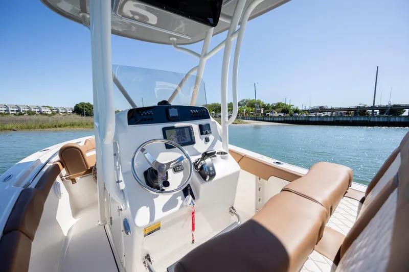 Slide: The Image of 2022 Pioneer 202 Islander boat interior with steering wheel and seating, docked by the water. - 18