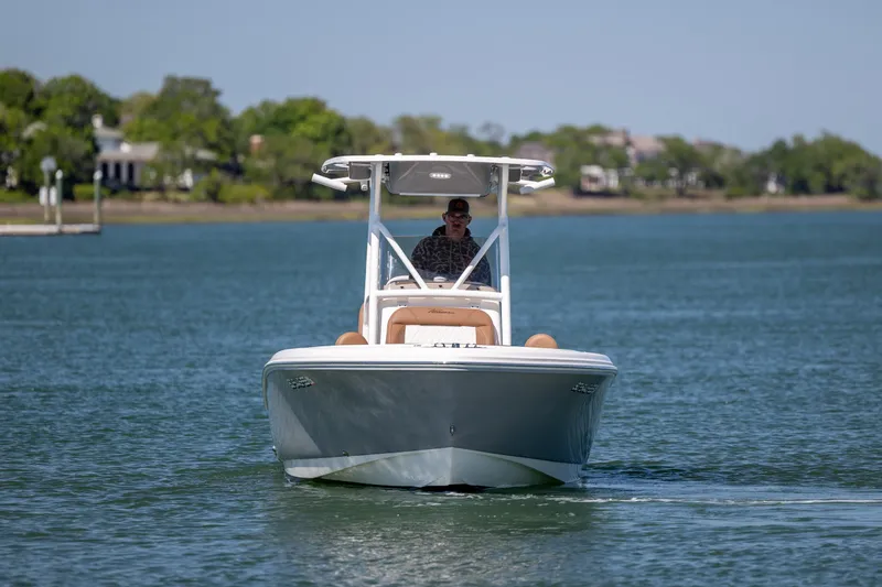 Slide: The Image of 2022 Pioneer 202 Islander boat cruising on a calm lake with lush green shoreline. - 5