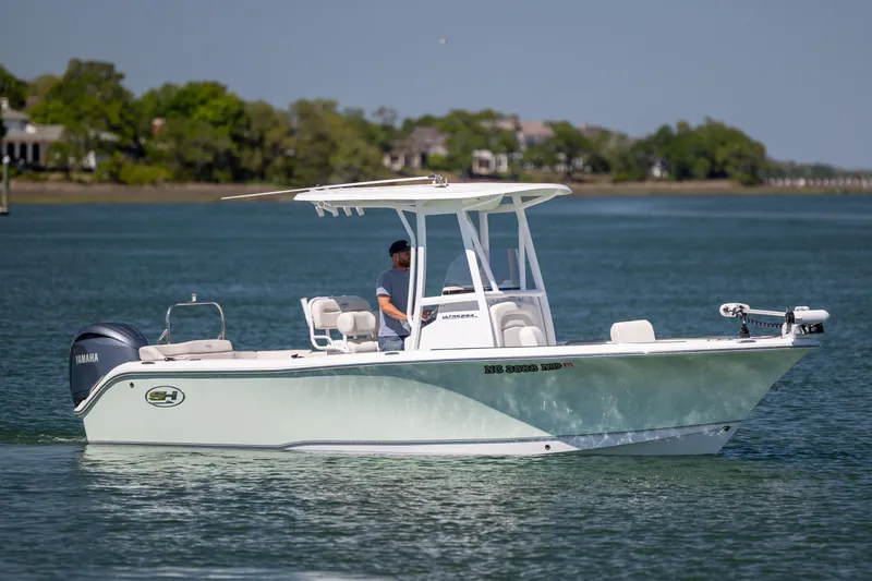 The Image of 2024 Sea Hunt Ultra 234 boat cruising on a serene lake with lush greenery. - 0