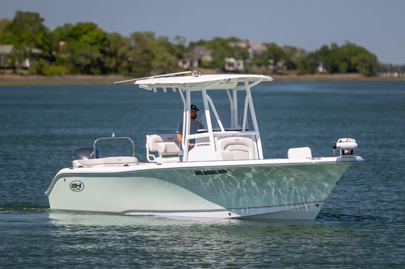 Slide: The Image of 2024 Sea Hunt Ultra 234 boat cruising on a calm lake with lush greenery. - 2