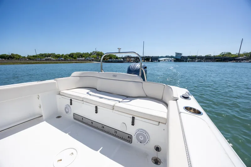 Slide: The Image of 2024 Sea Hunt Ultra 234 boat interior with seating, on a sunny day near a bridge. - 20
