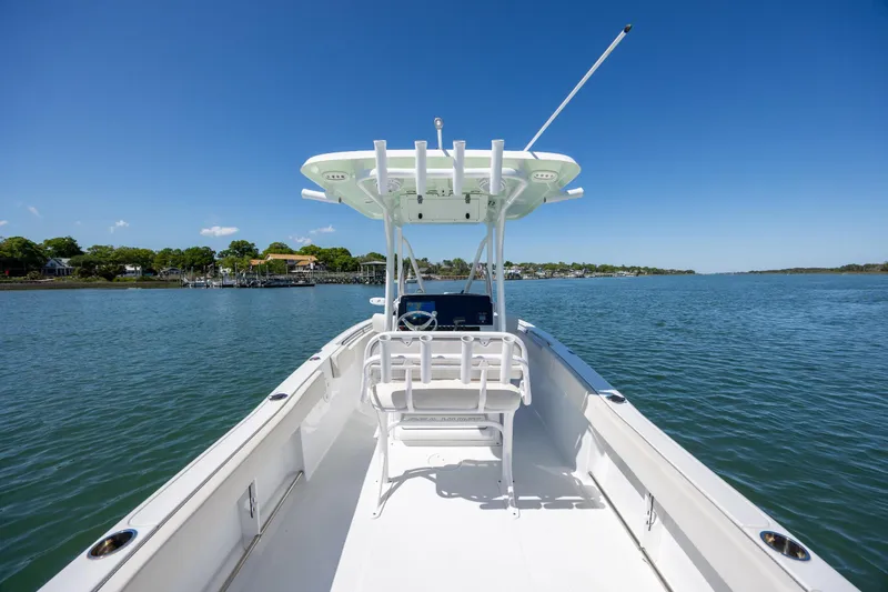 Slide: The Image of 2024 Sea Hunt Ultra 234 boat on calm water under clear blue sky. - 23