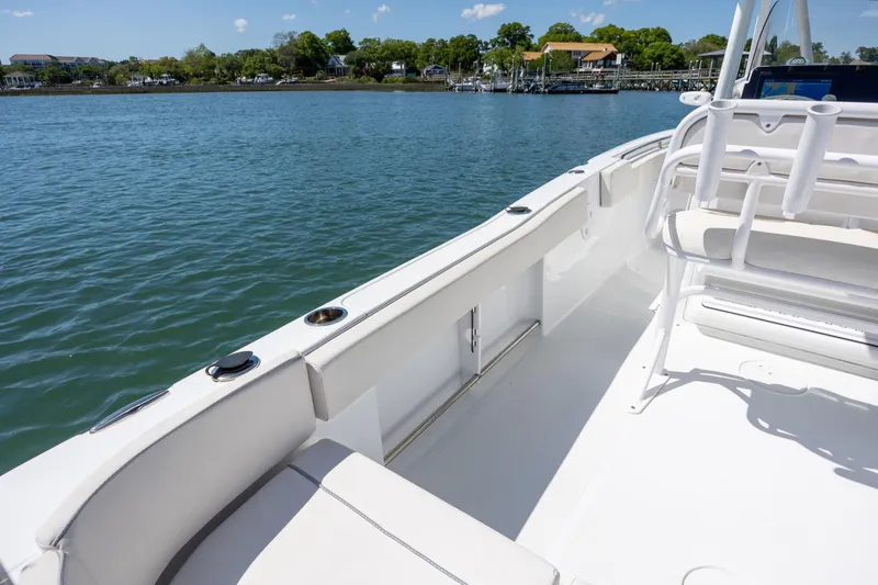 Slide: The Image of 2024 Sea Hunt Ultra 234 boat interior with seating, on calm water. - 24