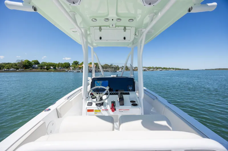 Slide: The Image of 2024 Sea Hunt Ultra 234 boat interior with steering console on calm water. - 26