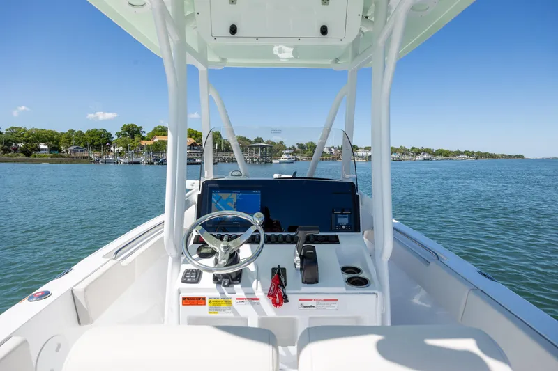Slide: The Image of 2024 Sea Hunt Ultra 234 boat dashboard with steering wheel and navigation system on calm water. - 27