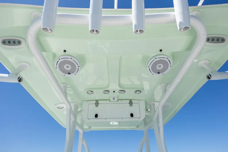 Slide: The Image of 2024 Sea Hunt Ultra 234 boat T-top with speakers and rod holders against blue sky. - 28