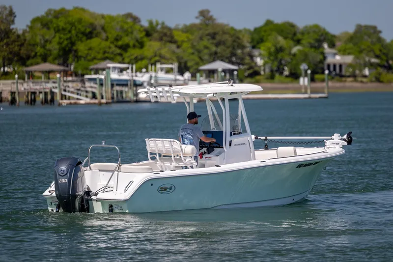 Slide: The Image of 2024 Sea Hunt Ultra 234 boat cruising on a serene lake with lush greenery in the background. - 3