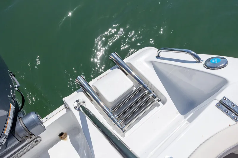 Slide: The Image of 2024 Sea Hunt Ultra 234 boat ladder and platform, reflecting sunlight on water. - 34