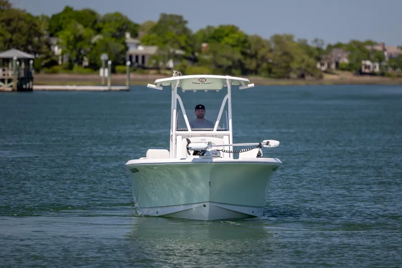 Slide: The Image of 2024 Sea Hunt Ultra 234 boat cruising on a calm lake with lush greenery. - 4