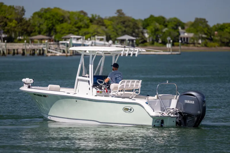Slide: The Image of 2024 Sea Hunt Ultra 234 boat cruising on a calm lake with Yamaha engine. - 8