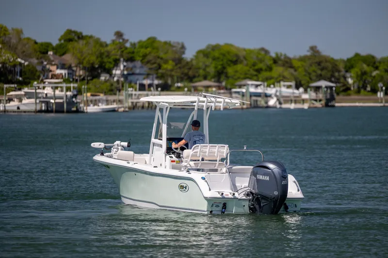 Slide: The Image of 2024 Sea Hunt Ultra 234 boat cruising on a calm lake with scenic background. - 9