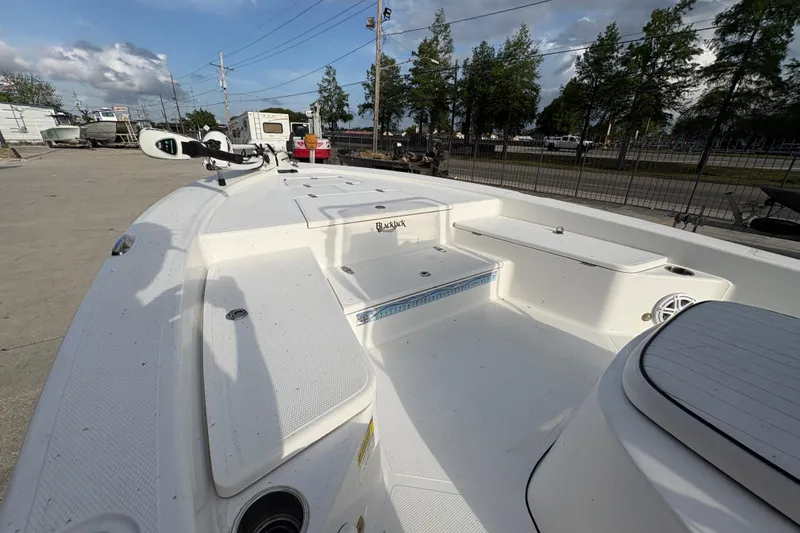 Slide: The Image of 2012 BlackJack 224 boat deck with seating and storage, parked outdoors. - 12