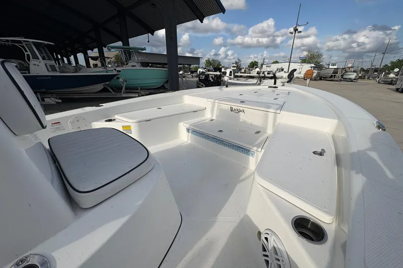 Slide: The Image of 2012 BlackJack 224 boat interior with seating and storage, displayed in a marina setting. - 13