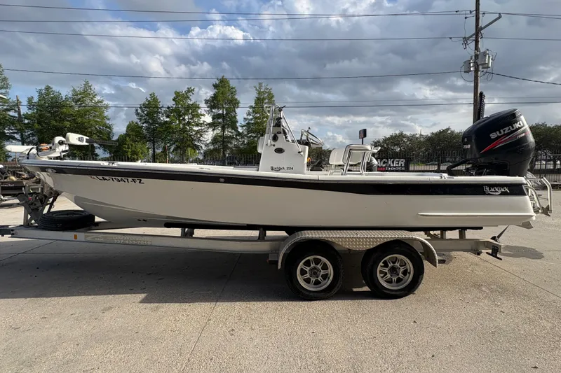 Slide: The Image of 2012 BlackJack 224 boat on trailer with Suzuki engine, parked outdoors. - 7