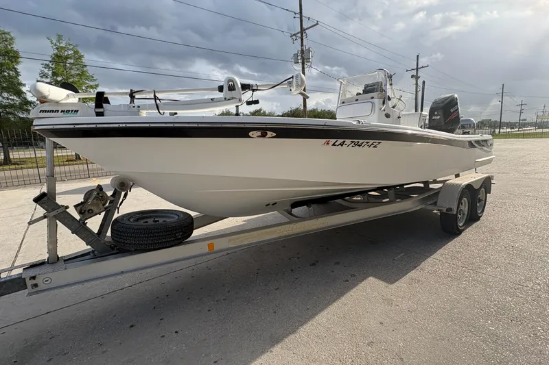 Slide: The Image of 2012 BlackJack 224 boat on trailer, featuring Minn Kota motor, parked outdoors. - 8