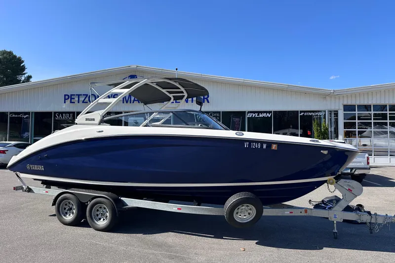 The Image of 2021 Yamaha Boats 252S on trailer outside dealership under clear blue sky. - 0