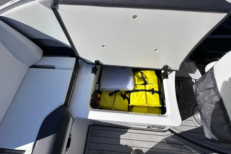 Slide: The Image of Open storage compartment on 2021 Yamaha Boats 252S with yellow life jackets inside. - 28