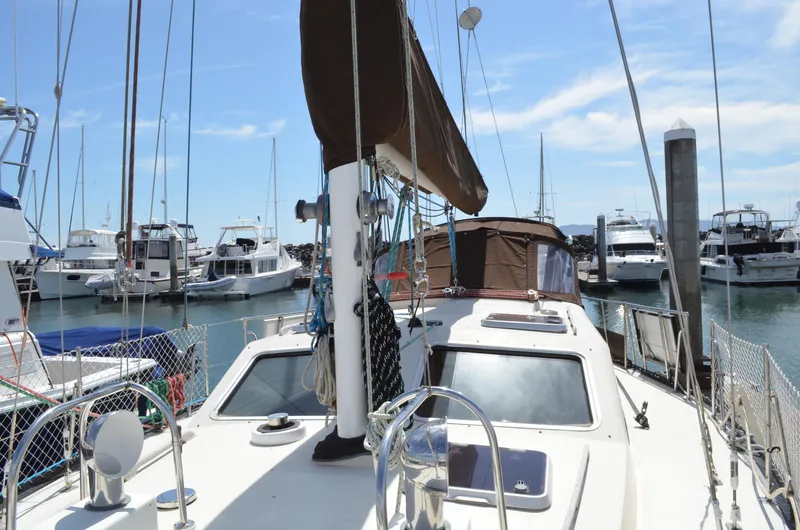 Slide: The Image of 1980 Cooper 416 Pilothouse sailboat docked in a marina under a clear blue sky. - 12