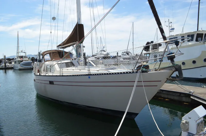 Slide: The Image of 1980 Cooper 416 Pilothouse sailboat docked in marina, clear sky background. - 2