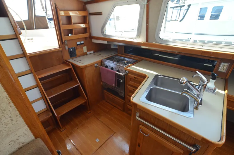 Slide: The Image of 1980 Cooper 416 Pilothouse interior with wooden cabinetry, dual sink, and staircase. - 26