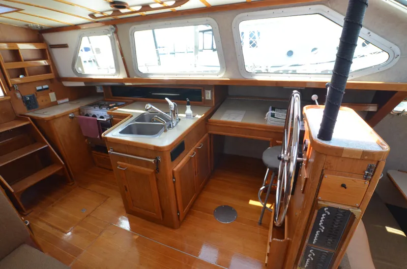Slide: The Image of 1980 Cooper 416 Pilothouse interior with wooden cabinetry, steering wheel, and kitchen area. - 28