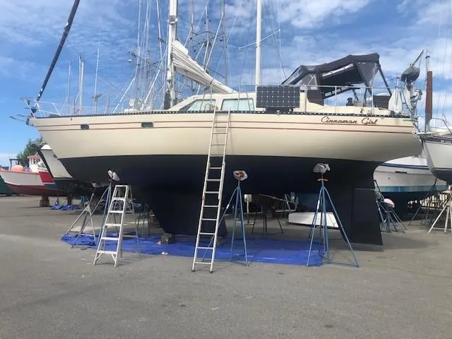 Slide: The Image of 1980 Cooper 416 Pilothouse sailboat on stands in a boatyard, with ladders and clear sky. - 45