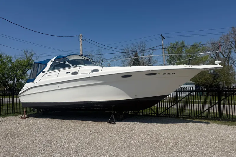 The Image of 1996 Sea Ray Sundancer 330 boat on display, parked on gravel, under clear blue sky. - 0