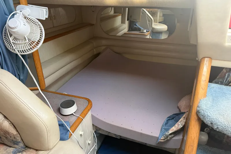 Slide: The Image of 1996 Sea Ray Sundancer 330 cabin interior with bed, fan, and wooden accents. - 19